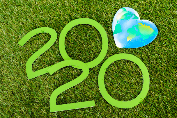 Vista superior de dígitos 2020 y globo sobre fondo verde, concepto del día de la tierra
 - Foto, Imagen