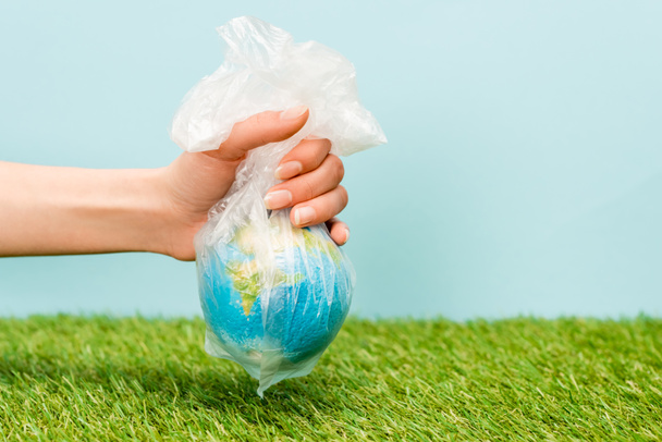 Vista recortada de la mujer sosteniendo bolsa de plástico con globo en verde y azul, concepto de calentamiento global
 - Foto, Imagen