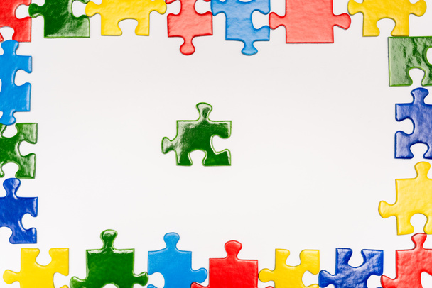 Top view of frame with bright pieces of puzzle on white background, autism concept - Foto, Imagen