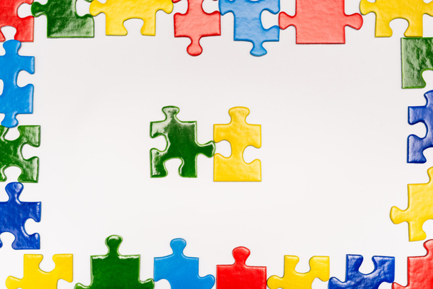 Vista superior del marco con piezas multicolores de rompecabezas sobre fondo blanco, concepto de autismo
 - Foto, imagen
