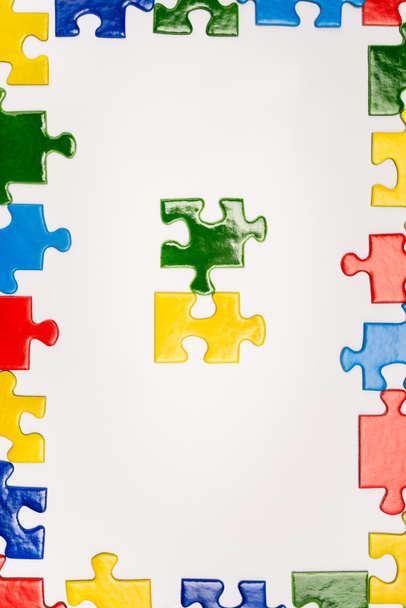 Top view of frame with bright multicolored pieces of puzzle isolated on white, autism concept - Fotoğraf, Görsel
