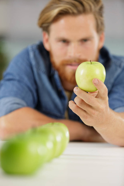 picture of man looking at a green apple - Foto, imagen