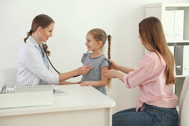 Mother and daughter visiting pediatrician. Doctor examining little patient with stethoscope in hospital - Foto, imagen