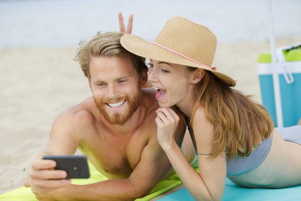 happy seflie couple taking picture with smartphone on beach - Foto, Bild