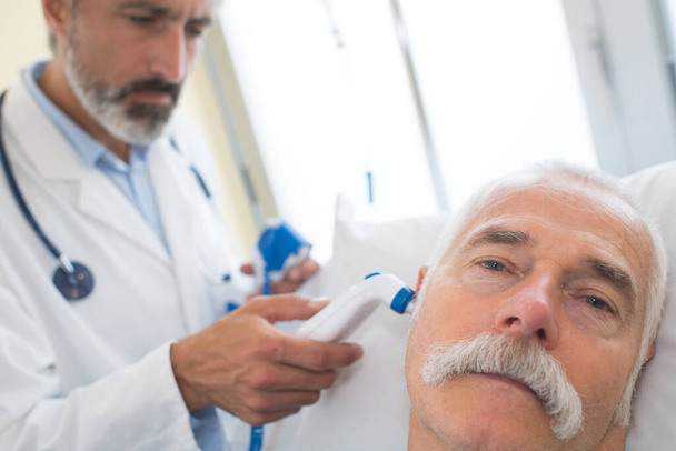 ein Arzt überprüft das Ohr des Patienten - Foto, Bild