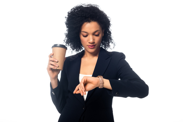 Front view of african american woman with disposable cup of coffee looking at wristwatch isolated on white - Foto, immagini
