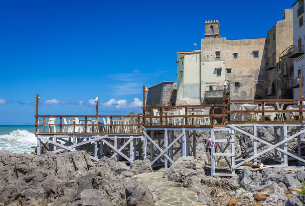 İtalya 'nın Sicilya Adası' ndaki Cefalu şehrindeki Tyrhenian deniz kıyısında, arka planda Santa Maria dell Itria kilisesi görülüyor. - Fotoğraf, Görsel