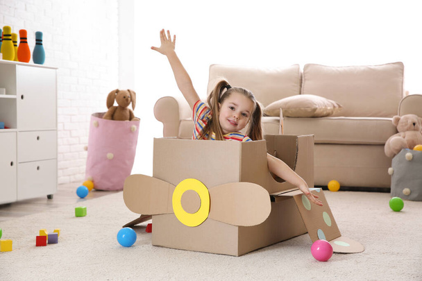 Cute little child playing with cardboard plane at home - Photo, Image