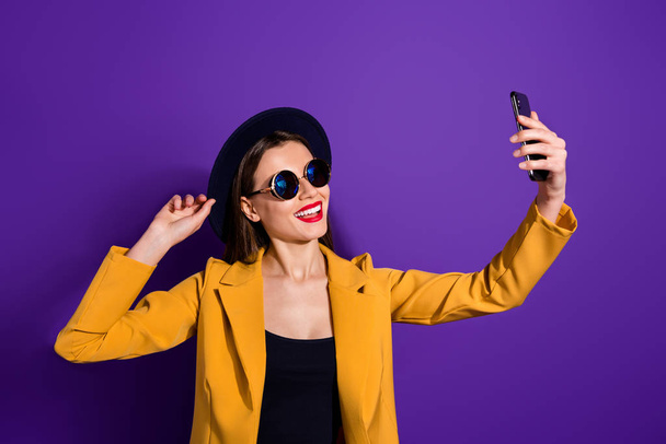Turned photo of cheerful lovely cute girl travel video blogging make selfie on multimedia device cellphone touch her velvet hat wear good look outfit isolated over purple color background - Fotoğraf, Görsel