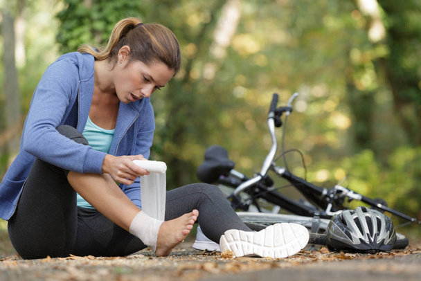 sportwoman bandaging her painful ankle injury outside - Zdjęcie, obraz