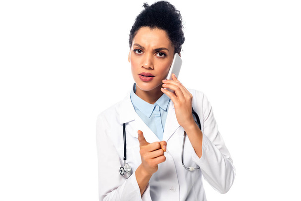 Front view of worried african american doctor with stethoscope talking on smartphone isolated on white - Photo, Image