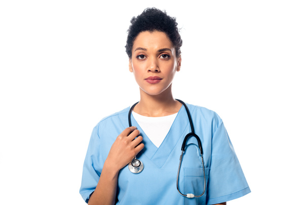 Vista frontal de enfermera afroamericana con estetoscopio mirando cámara aislada en blanco
 - Foto, imagen