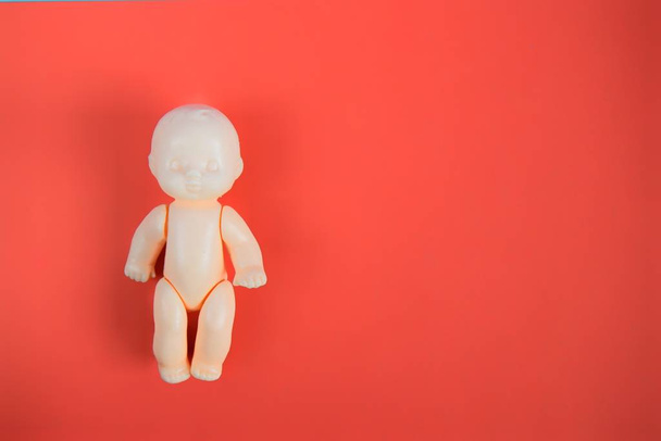 one children's toy doll for children from one year on a red background with a place for the inscription. close up - Zdjęcie, obraz