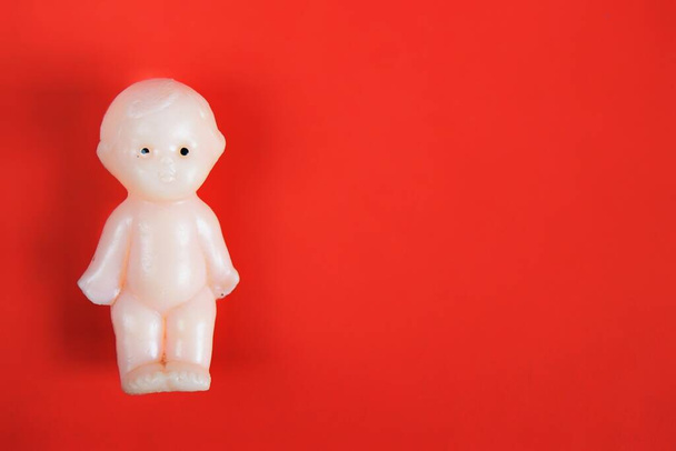 one children's toy doll for children from one year on a red background with a place for the inscription. close up - Fotó, kép