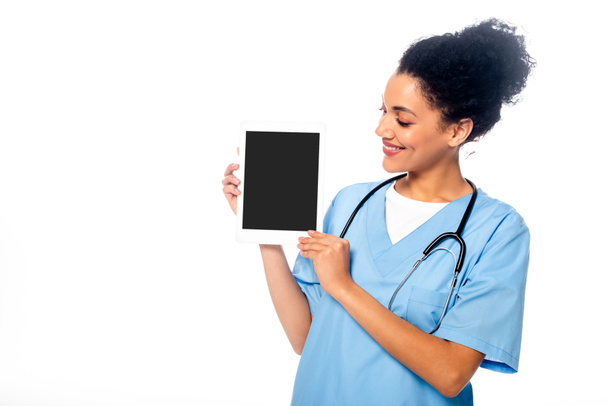African american nurse smiling and showing digital tablet isolated on white - Foto, afbeelding