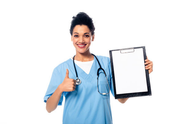 Front view of african american nurse with stethoscope showing clipboard and thumb up isolated on white - Fotografie, Obrázek