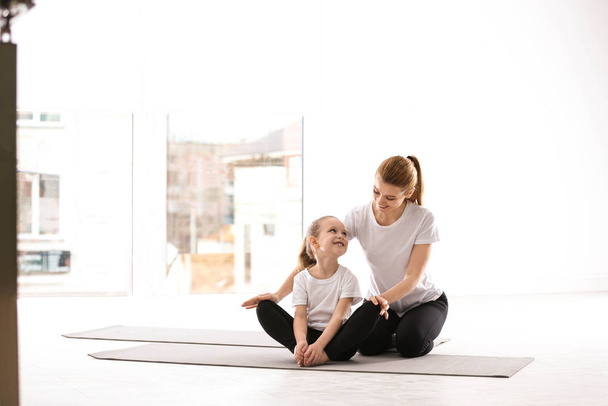 Mother and daughter in matching sportswear doing yoga together at home - Foto, immagini