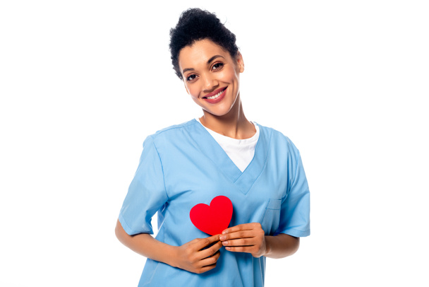 Счастливая и позитивная африканская медсестра, представляющая декоративное сердце, изолированное на белом
 - Фото, изображение