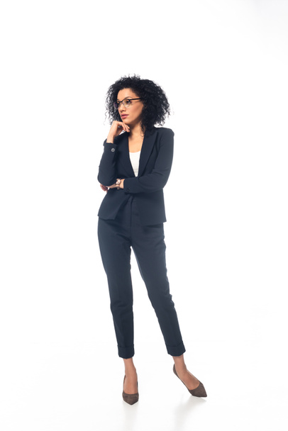 Full length view of confident african american businesswoman in suit with glasses on white background - Photo, Image