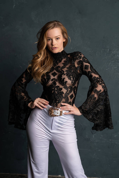 Beautiful tall blonde woman in a black lace blouse and white slacks - Fotografie, Obrázek