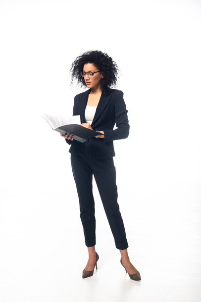 Full length view of african american businesswoman looking in folder on white background - Foto, Bild