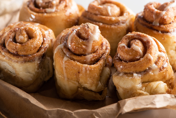 close up view of fresh delicious homemade cinnamon rolls on parchment paper - Fotoğraf, Görsel