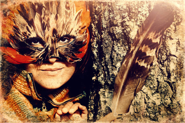 カラフルな羽の顔のマスクを持つ若い女性は、古い写真効果. - 写真・画像