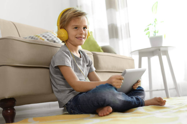 Cute little boy with headphones and tablet listening to audiobook at home - Foto, Imagem