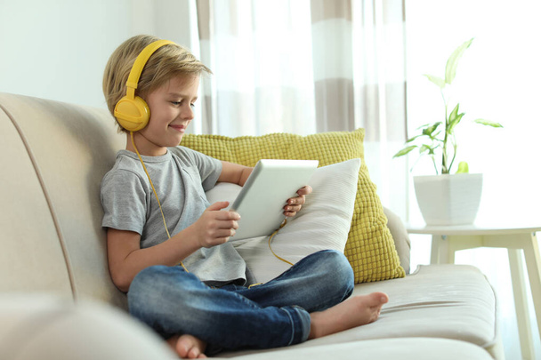 Cute little boy with headphones and tablet listening to audiobook at home - Foto, imagen