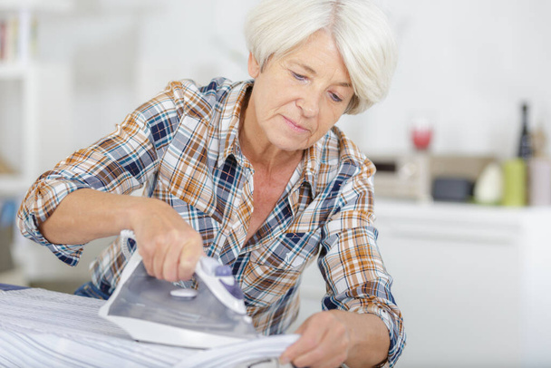 a senior woman ironing clothes - Foto, Imagen
