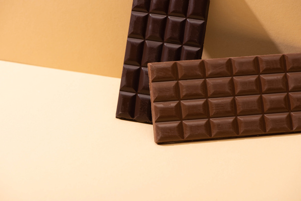 doce delicioso escuro, barras de chocolate com leite no fundo bege
 - Foto, Imagem