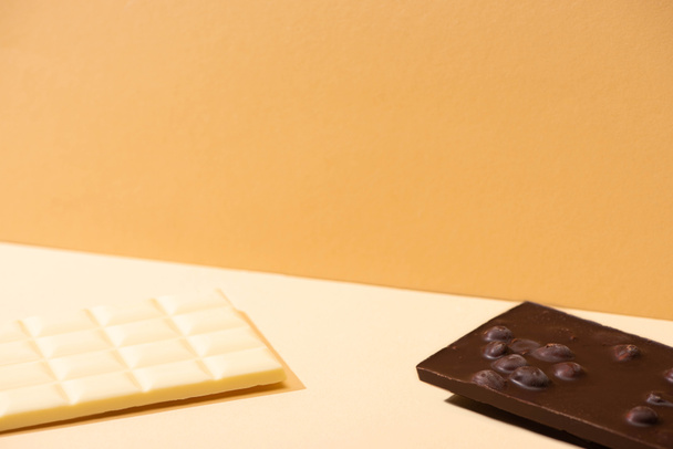 delicious broken white and dark chocolate bars with nuts on beige background - Fotó, kép