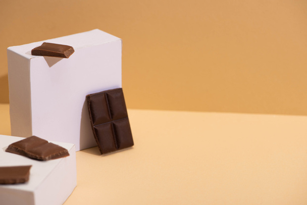 deliciosos pedaços de chocolate escuro e leite e cubos quadrados no fundo bege
 - Foto, Imagem