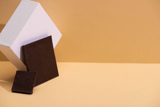 delicious dark chocolate pieces and cube on beige background - Fotoğraf, Görsel