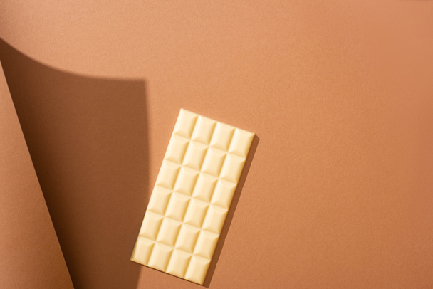 selective focus of delicious whole white chocolate bar on brown background with paper - Foto, Imagen