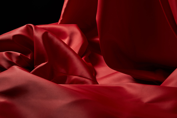 close up view of red soft and crumpled silk textured cloth isolated on black - Foto, afbeelding