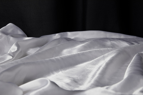 закрытый вид белой мягкой и измятой шелковой текстуры ткани, изолированной на черном
 - Фото, изображение