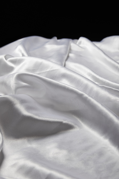 close up view of white soft and crumpled silk textured cloth isolated on black - Foto, afbeelding