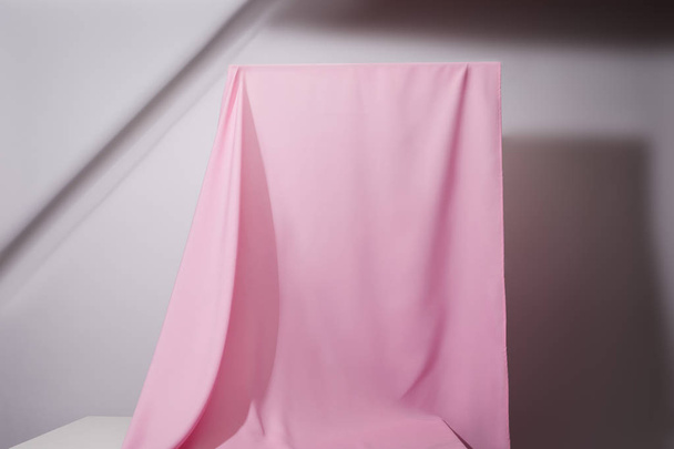 ροζ μαλακό κυματιστό ύφασμα που κρέμεται σε γκρι φόντο - Φωτογραφία, εικόνα