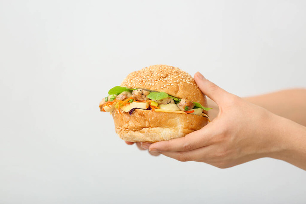 Женские руки с вкусным кебабом в булочке на светлом фоне
 - Фото, изображение