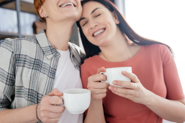 sourire même sexe coupé tenant tasses à café à la maison
 - Photo, image