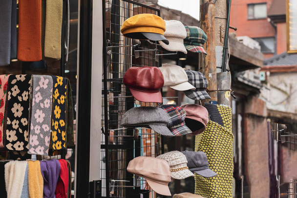 Různé ženy stylový klobouk vystaven před obchodem. Ročník podzim módní baret čepice a květinový vzor šála. - Fotografie, Obrázek