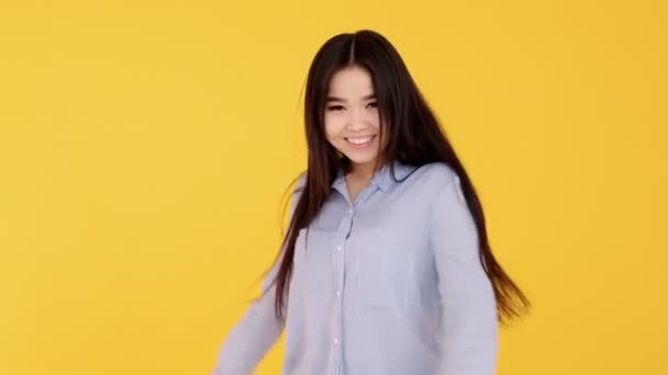 Dívka asijské úsměv široce na žlutém pozadí žena při pohledu na kameru - Záběry, video