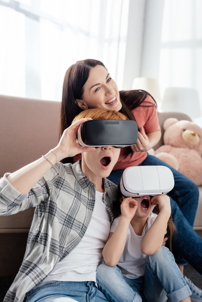 Shocked child using vr headsets with mothers in living room - Fotografie, Obrázek