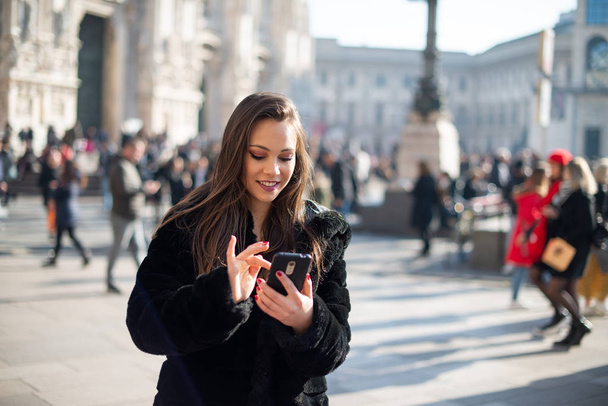 Woman using her smartphone while walking in an European city - Fotó, kép