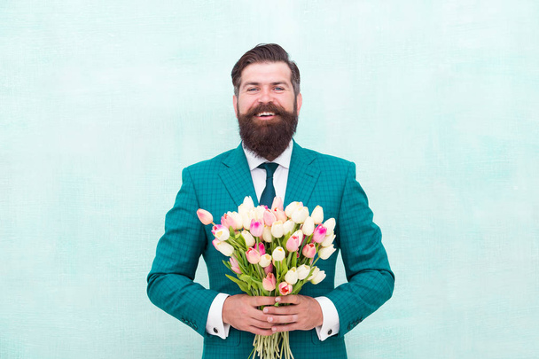 Hello summer. bearded man in formal suit greeting. happy valentines day. womens day gift tulips. spring flowers. Man with bouquet tulips. prepare for mothers day holiday. flower surprise for her - Фото, изображение