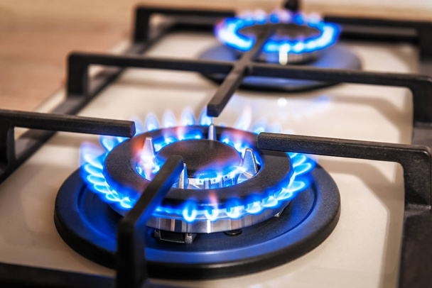 Close-up shot van blauw vuur van huishoudelijke keukenfornuis top. Gasfornuis met brandende vlammen van propaangas. Begrip industriële hulpbronnen en economie. - Foto, afbeelding