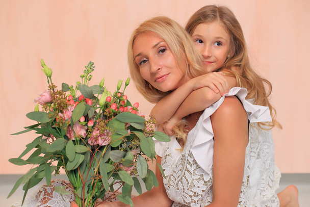 Mom with her daughter in white dresses in the studio. - Foto, imagen