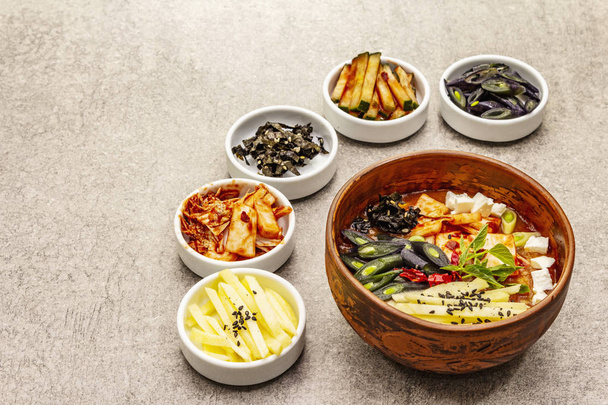 Traditional Korean spicy soup with kimchi, tofu, vegetables. Hot dish for healthy meal. Stone concrete background, copy space - Zdjęcie, obraz