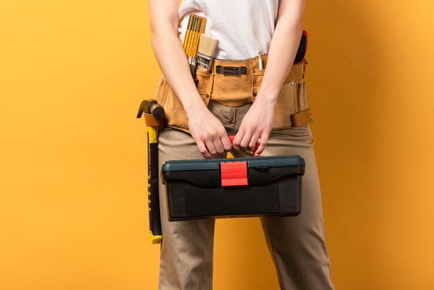 cropped view of handywoman holding toolbox on yellow background  - Fotoğraf, Görsel